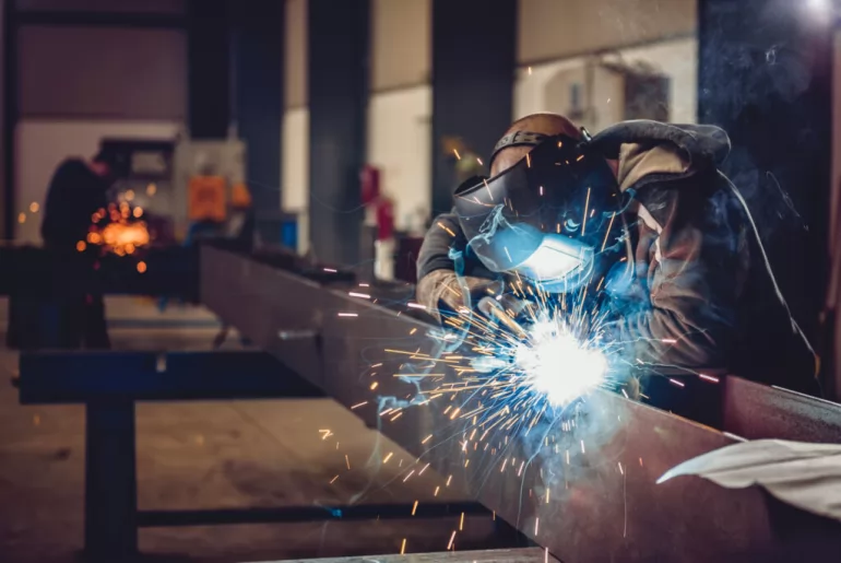 a welder welds industrial equipment